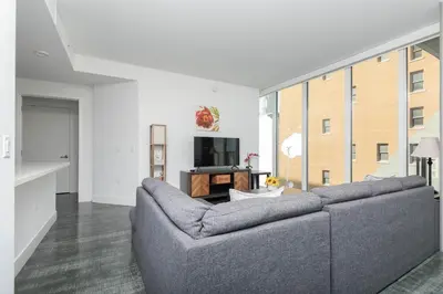 a living room with a gray couch and a tv at 3-Bed High-Rise with Panoramic Views, Pool & Spa in Los Angeles
