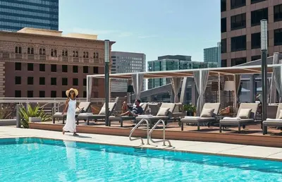 a woman standing next to a swimming pool on a building at 3-Bed High-Rise with Panoramic Views, Pool & Spa in Los Angeles