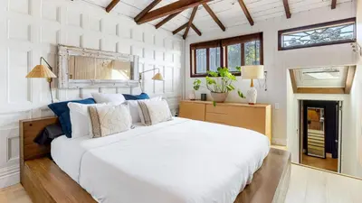 a white bedroom with a large white bed and windows at Chic LA Hideaway w Soaking Tub Firepit Lounge Tranquil Backyard in Los Angeles
