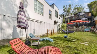a yard with chairs and an umbrella next to a building at Chic LA Hideaway w Soaking Tub Firepit Lounge Tranquil Backyard in Los Angeles