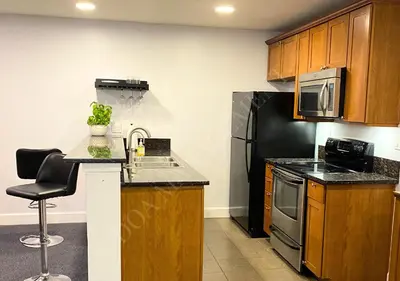 a kitchen with wooden cabinets and a sink and a refrigerator at Luxury condo in the heart of LA in Los Angeles