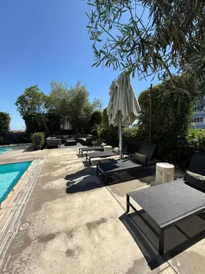 a group of lounge chairs and an umbrella next to a pool at Seven Mile Penthouse Dream Hollywood View Pool in Los Angeles
