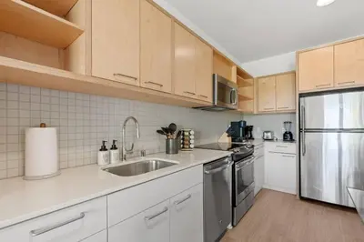 a kitchen with white cabinets and a stainless steel refrigerator at Emerald Ridge - Luxe Hollywood Walk of Fame in Los Angeles