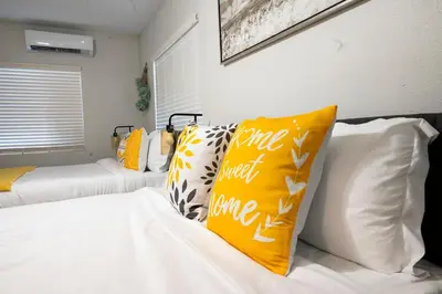 a bedroom with two beds with yellow and white pillows at Relaxing Cozy Back House with Backyard in Upland