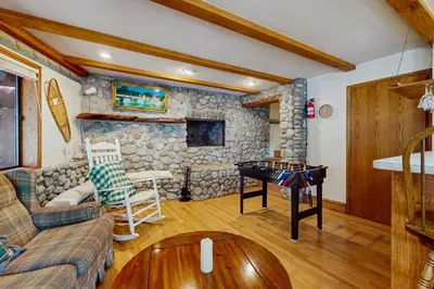 a living room with a table and a stone wall at Villa Elvira in Lake Arrowhead