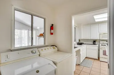 a kitchen with white cabinets and a large window at 12 Mi to Dtwn LA Family Home with Patio and Yard! in Downey