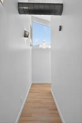 an empty white room with a window and a wooden floor at Your Coastal Getaway in Manhattan Beach Awaits in Manhattan Beach