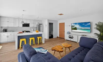 a living room with a blue couch and a kitchen at Your Coastal Getaway in Manhattan Beach Awaits in Manhattan Beach