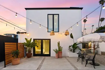 a white house with a patio with potted plants and lights at Luxe 2BR with Designer Touches, Walk to Everything in Los Angeles