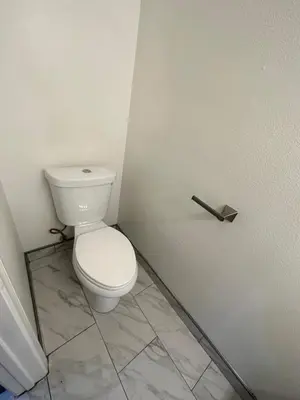 a white toilet in a bathroom with a tile floor at Echo House in Los Angeles