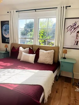 a bedroom with a large bed with two windows at Cozy Hollywood Cottage - Free Parking in Los Angeles