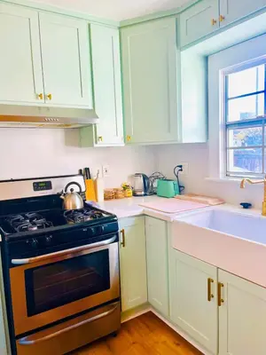 a kitchen with white cabinets and a stove and a sink at Cozy Hollywood Cottage - Free Parking in Los Angeles