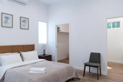 a white bedroom with a bed and a chair at New 2BR Family Home Nr Universal in Gemco