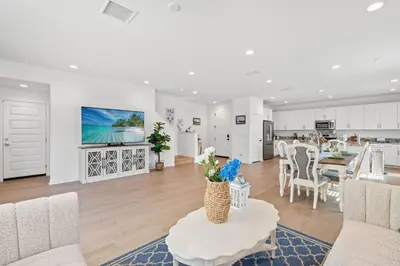 a white living room with a table and a kitchen at Spacious 5BR Getaway w Game Room & Modern Comfort in Fontana
