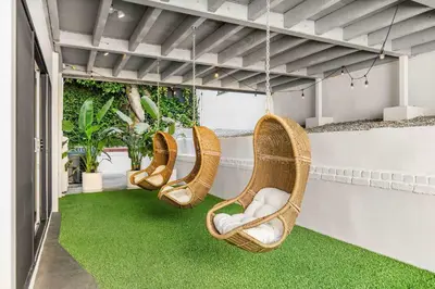 three wicker chairs hanging on a balcony with green grass at Villa Incanto in Los Angeles