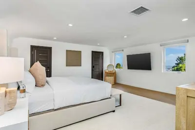 a white bedroom with a bed and a flat screen tv at Villa Incanto in Los Angeles