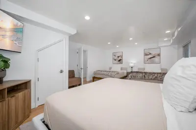 a white bedroom with a bed and a living room at Ocean Views in Long Beach in Long Beach