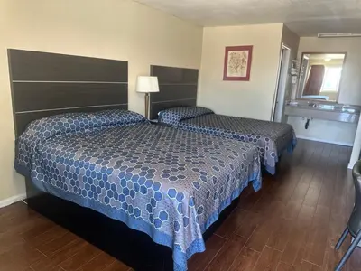 a hotel room with two beds and a sink at Mayfair Inn Onratio Airport & Convention Center in Ontario
