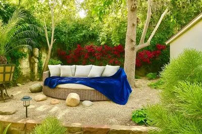 a couch with a blue blanket sitting in a garden at Enchanting Private Hollywood Hills Guest House with Tranquil Tree-Top Views, Magical Outdoor Living Room and Patio and Zen Garden, In LA's Most Desirable, Central, Serene Area and Only 2 Minutes from Hollywood Boulevard in Los Angeles