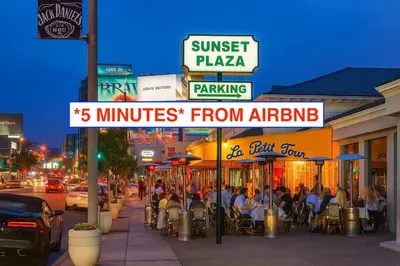 a city street with people sitting at tables on a sidewalk at Enchanting Private Hollywood Hills Guest House with Tranquil Tree-Top Views, Magical Outdoor Living Room and Patio and Zen Garden, In LA's Most Desirable, Central, Serene Area and Only 2 Minutes from Hollywood Boulevard in Los Angeles