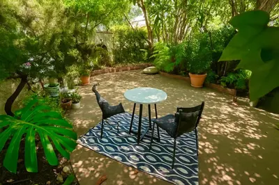 a patio with a table and chairs in a garden at Enchanting Private Hollywood Hills Guest House with Tranquil Tree-Top Views, Magical Outdoor Living Room and Patio and Zen Garden, In LA's Most Desirable, Central, Serene Area and Only 2 Minutes from Hollywood Boulevard in Los Angeles