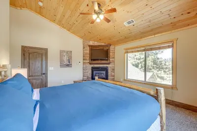a bedroom with a bed with a ceiling fan and a fireplace at Walkable Big Bear Lake Home with Private Hot Tub! in Big Bear Lake