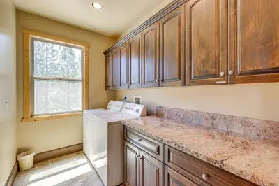 a kitchen with wooden cabinets and a washer and dryer at Walkable Big Bear Lake Home with Private Hot Tub! in Big Bear Lake