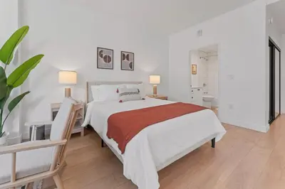 a white bedroom with a large bed and a plant at Stylish LA studio Prime Location in Los Angeles