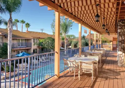 a patio with tables and chairs next to a pool at Wyndham Dolphin's Cove 2BR Suite with Resort Access in Anaheim