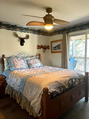 a bedroom with a bed with a ceiling fan at Best View of the Lake! Huge Deck! in Crestline