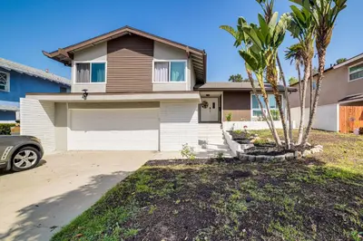 a house with a garage and a palm tree at Golf, Swim, Relax Family Retreat in Corona! in Corona
