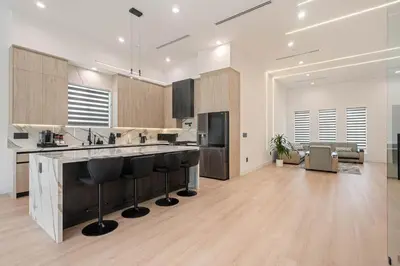 a large kitchen with a counter and stools at The Valley Nest Backyard Gameroom in Los Angeles