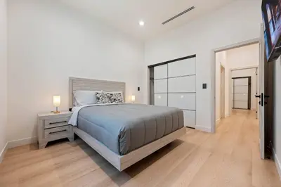 a white bedroom with a large bed and a window at The Valley Nest Backyard Gameroom in Los Angeles