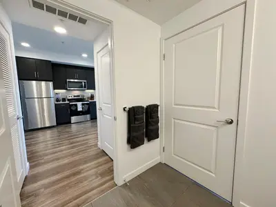 a hallway with a white door and a kitchen at Modern 1BR Apartment with Pool, Hot Tub and Gym Access 10mins to Universal Studios in Los Angeles