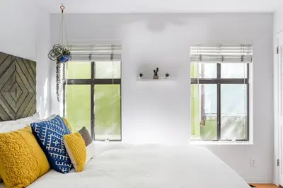 a bedroom with a white bed and two windows at Silver Triangle Oasis with Verdant Backyard in Los Angeles