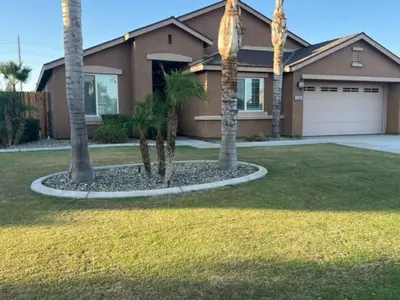 a house with palm trees in front of it at Cadbury 4BR Outdoor Kitchen Sleeps 8 Peaceful in Bakersfield