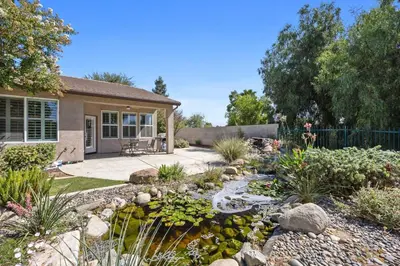 a garden with a pond in front of a house at Luxury Gated Retreat Golf Course Views Sleeps 8 in Bakersfield