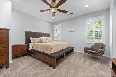 a bedroom with a bed and a ceiling fan and a chair at Luxury Gated Retreat Golf Course Views Sleeps 8 in Bakersfield