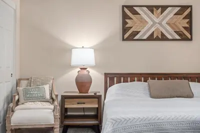 a bedroom with a bed and a chair and a lamp at Modern Southwest Escape 2 Master Bedrooms in Bakersfield