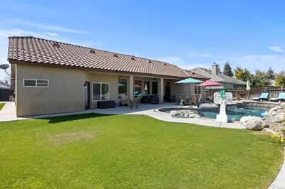 a house with a swimming pool and a yard at Spacious 4BR 3BA Home KING Suite Pool Sleeps 8 in Bakersfield