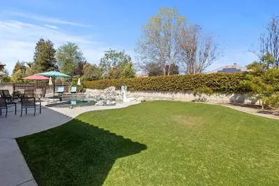 a garden with a lawn and a table and chairs at Spacious 4BR 3BA Home KING Suite Pool Sleeps 8 in Bakersfield