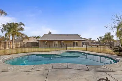 a swimming pool in front of a house at Windward Bay Executive 3BR Office Home Pool in Bakersfield