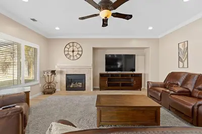 a living room with a ceiling fan and a fireplace at Windward Bay Executive 3BR Office Home Pool in Bakersfield