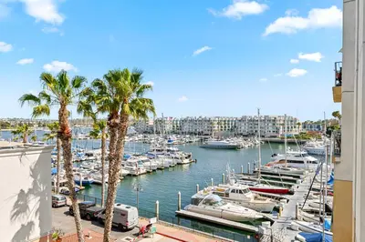 a marina with boats in a harbor with palm trees at Acacia Waterfront Marina Views Pool Gym Jacuzzi And Sauna in Los Angeles