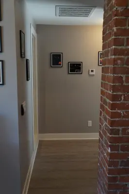 a hallway with a brick wall and framed pictures at The Jazz Room - Executive Suite Downtown Riverside in Riverside