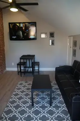 a living room with a couch and a tv on the wall at The Jazz Room - Executive Suite Downtown Riverside in Riverside