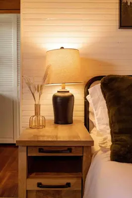 a lamp on a table next to a bed at Little Wolf Lodge Modern Cabin at Lake Gregory in Crestline