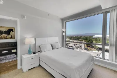 a white bedroom with a bed and a large window at Global Luxury Suites in LA's Seaside in Los Angeles