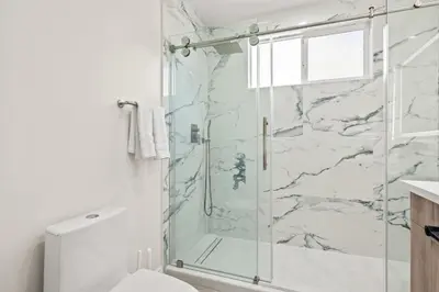 a bathroom with a shower with a glass door at Modern New 3B Home Fully Stocked & Cozy & Sunlight