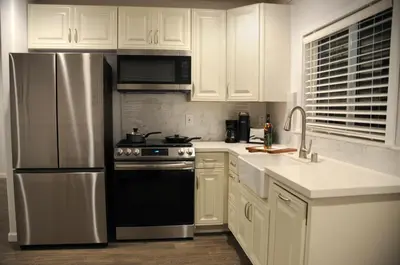 a kitchen with white cabinets and a stainless steel refrigerator at Champagne Retreat in Upland